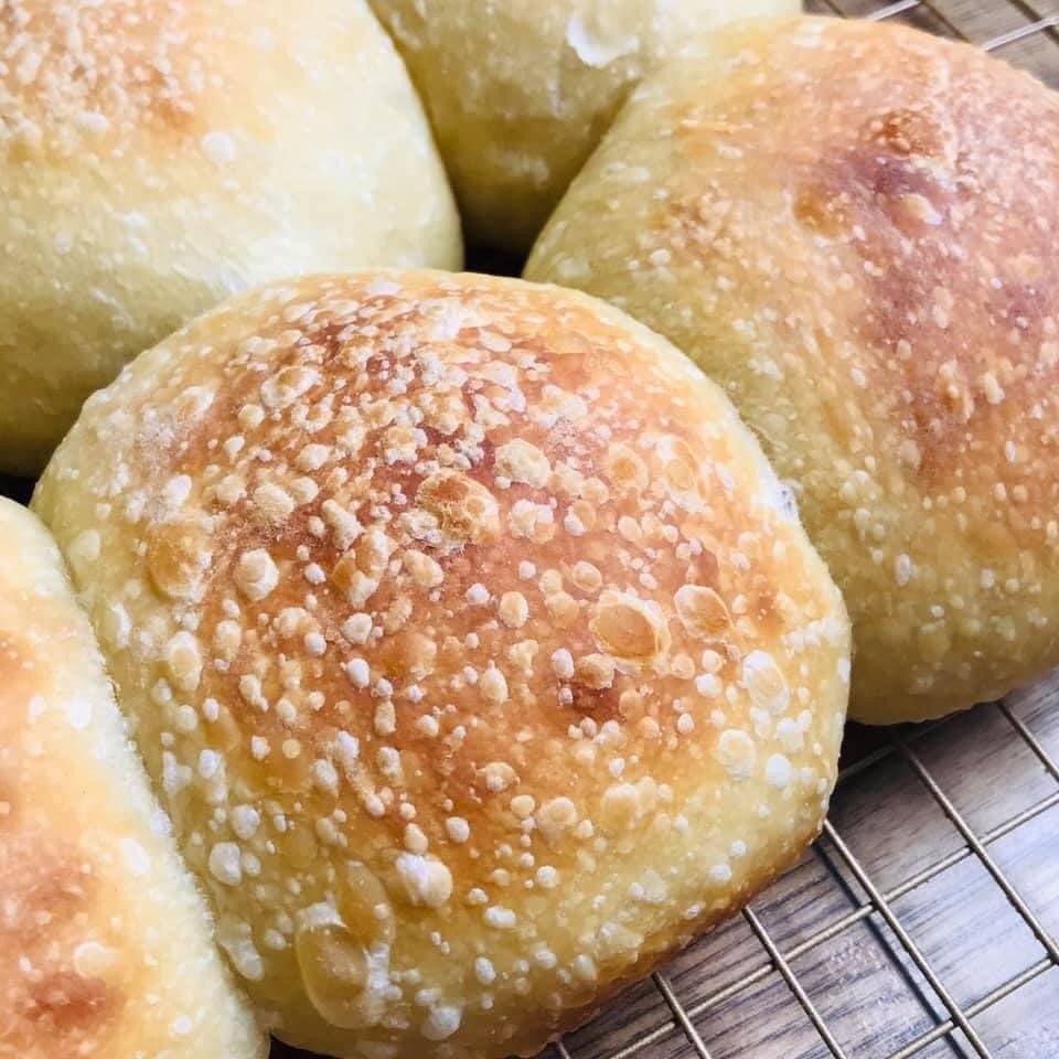 Golden, glossy baked brioche sourdough buns cooling on a wire rack