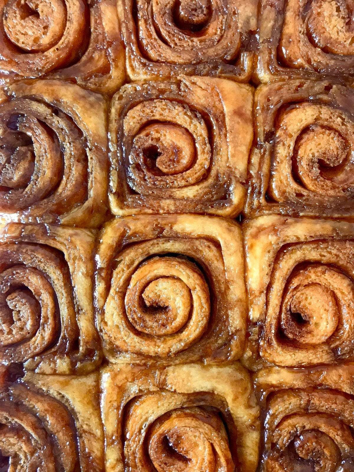A tray of caramel-glazed cinnamon buns swirled and glistening
