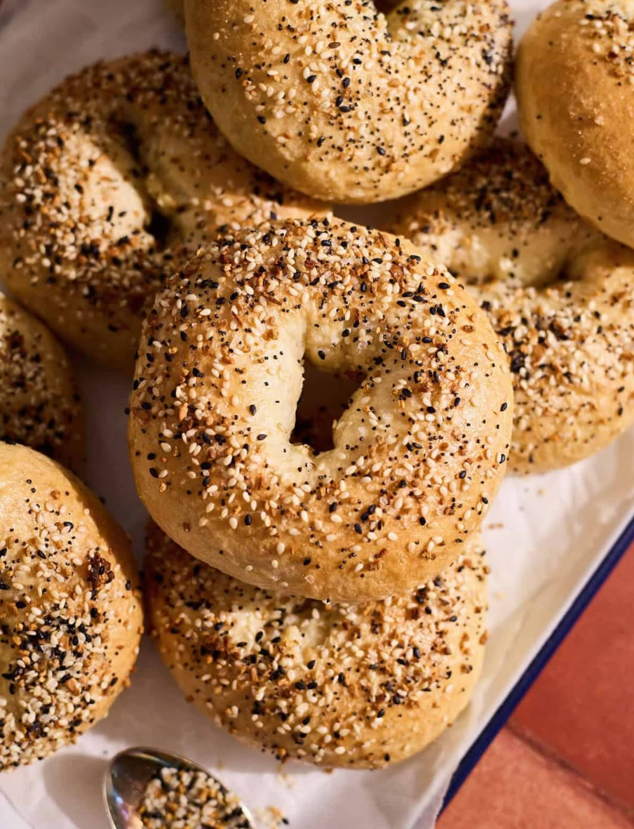 A pile of everything sourdough bagels crusted with sesame, poppy seeds, garlic and onion