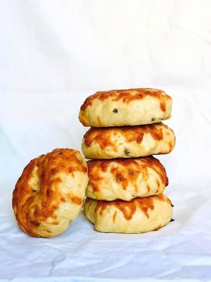 A stack of jalapeño cheddar sourdough bagels with melted cheese and green pepper flecks